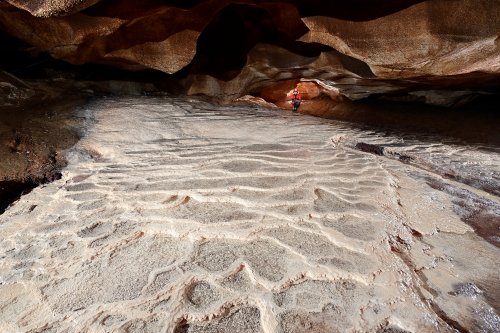 Grotte de Saint-Marcel d'Ardèche (Ardèche) - Réseau II : pente calcifiée avec micro gours blancs (spéléo en fond à droite)(SP-25-0100)