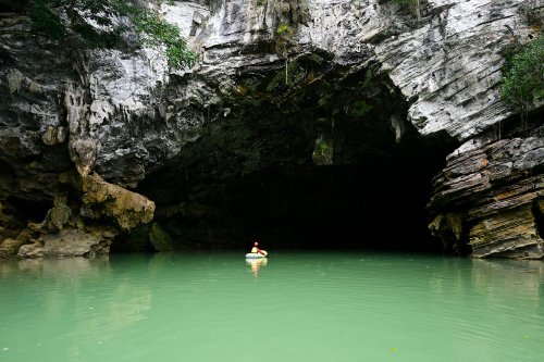 Tulan cave (Tan Hoa, Vietnam) - Entrée de la grotte vue de l'extérieur avec spéléo dans canot pneumatique sur la rivière(SP-25-0265)
