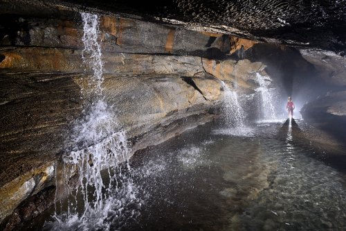 Hang Va cave (Phong Nha, Vietnam) - Série de cascades se déversant dans une rivière souterraine (avec spéléo en arrière-plan)(SP-25-0380)
