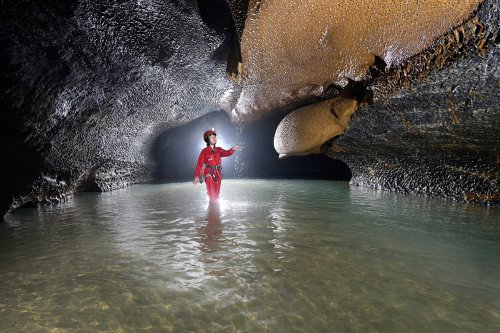 Hang Va cave (Phong Nha, Vietnam) - Coulées de calcite orange au dessus de la rivière (avec spéléo sous  cascatelle)(SP-25-0378)