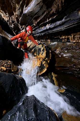 Caverna da Agua Suja (Sao Paulo, Brésil) - Spéléo descendant une petite cascade (roche noire et jaune)(SP-25-2210)