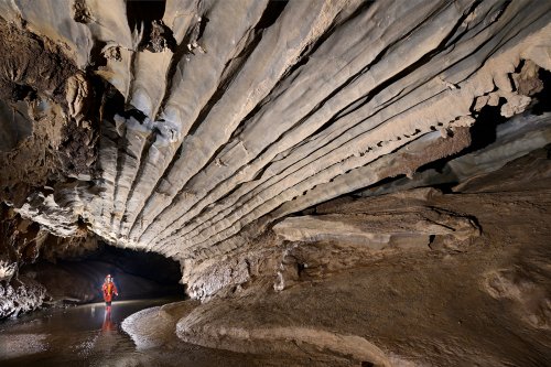 Caverna Alambari de Baixo (Sao Paulo, Brésil) - Plafond  avec bandes en relief au dessus de la rivière (spéléo en fond).(SP-25-2283)