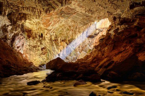 Lapa Terra Ronca (Goias, Brésil) - Grande galerie avec un rayon de soleil (spéléo sur rocher en silhouette dans le rayon et eau éclairée en premier plan).(SP-25-1935)