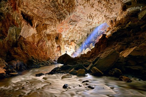 Lapa Terra Ronca (Goias, Brésil) - Grande galerie avec un rayon de soleil (spéléo sur rocher en silhouette et eau éclairée en premier plan).(SP-25-1909)