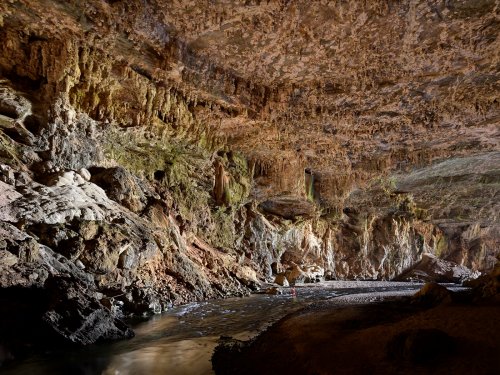 Lapa Terra Ronca (Goias, Brésil) - Galerie d'entrée éclairée par la lumière du jour avec spéléo dans la rivière(SP-25-1596)
