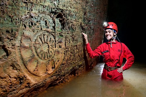 Caverna das Maos (Para, Brésil) - Spéléo regardant une gravure préhistorique représentant un mandala (SP-23-1260)