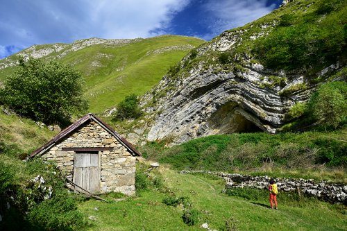 Grotte d'Harpéa (Pyrénées-Atlantiques) - Vue de la grotte avec cabane en pierre premier plan et randonneur (avec ciel) (HY-25-0097)