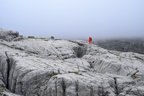 Arres d'Anie (Pierre Saint-Martin, Pyrénées Atlantiques) - Randonneuse sur lapiaz dans brouillard regardant un gouffre(MO-25-0028)