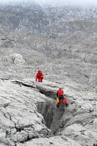 Arres d'Anie (Pierre Saint-Martin, Pyrénées Atlantiques) - Deux spéléos en rouge équipant un gouffre(MO-25-0043)
