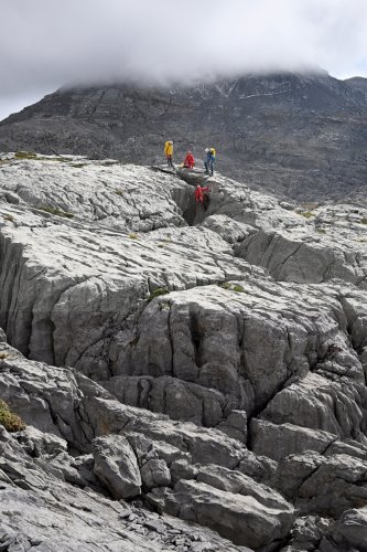 Arres d'Anie (Pierre Saint-Martin, Pyrénées Atlantiques) - Groupe de spéléos équipant un gouffre (lapiaz au soleil)(MO-25-0077)
