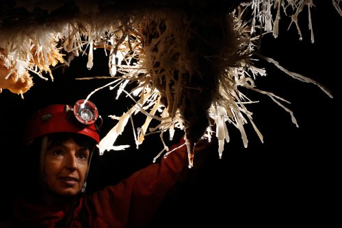 Aven des Crozes (Hérault) - Jeune femme derrière une stalactite avec des aiguilles d'aragonite(SP-09-0689)