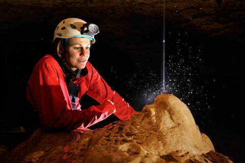 Grotte de la Cocalière (Gard) - Spéléo regardant filet d'eau tombant sur une stalagmite(SP-11-0801)