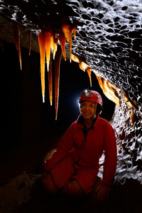 Grotta Gualterio Savi (région de Trieste, Italie) - spéléo assise regardant une stalactite orange(SP-13-1235)