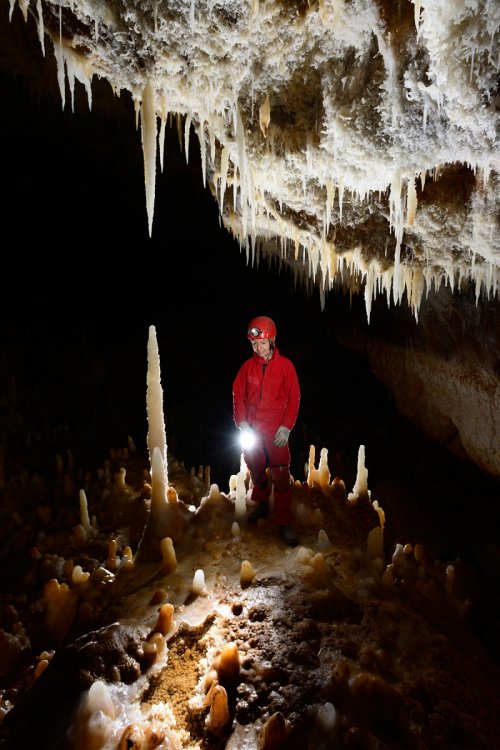 KotalehKhor Cave (Province de Zanjan, Iran) - Salle concrétionnée : spéléo au milieu des fistuleuses et des stalagmites éclairant un petit gour avec des cristaux  (SP-15-0042)