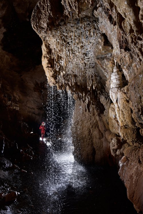 Waipuna Cave (Nouvelle Zélande) - Cascatelle arrivant dans une rivière souterraine avec spéléo en fond(SP-17-0937)