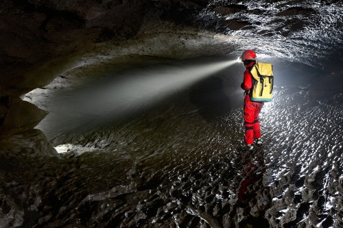 Grotte du Hölloch (Suisse) - Spéléo éclairant devant lui dans une conduite forcée(SP-18-1621)
