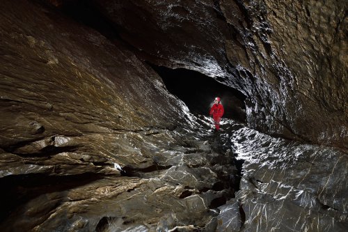 Grotte du Hölloch (Suisse) - Spéléo remontant une galerie érodée avec des calcaires gris au sol(SP-18-1632)