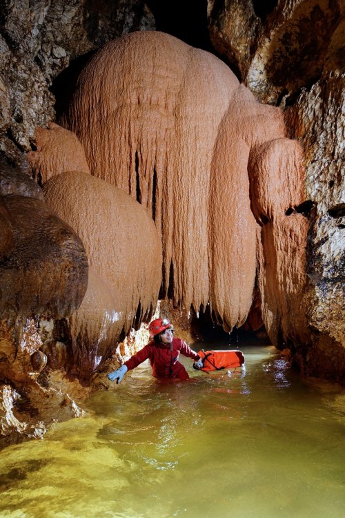 Pestera Sura Mare - Spéléo passant sous un dôme de calcite orange dans la rivière(SP-18-2007)