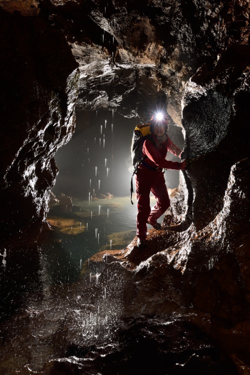 Akiyoshi-do (Akiyoshidai, Yamaguchi, Japon) - Spéléo progressant dans une petite galerie avec une petite cascatelle tombant du plafond (contre jour seul)(SP-19-0189)