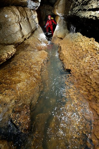 Rivière de la Vieille Folle (Doubs) - Progression dans la rivière souterraine avec coups de gouge sur les parois (spéléo en arrière plan)(SP-20-0427)