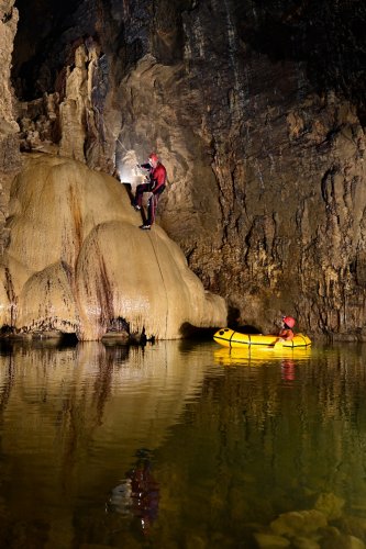 Grotte Sarrazine (Doubs) - Traversée en canot pneumatique du lac d'entrée avec spéléo descendant la coulée de calcite(SP-20-0459)