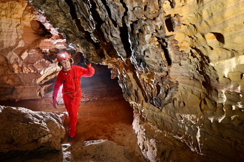 Caverna das Maos (Para, Brésil) - Spéléo regardant une paroi de grès érodé(SP-23-1143)