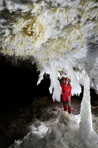 Grotte de Geophysicheskaya (Turkménistan) - Salle rose : chandeliers et stalagmite de gypse avec personnage en fond (vue générale).(SP-24-0903)
