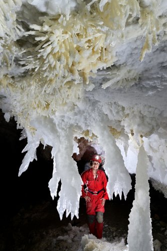 Grotte de Geophysicheskaya (Turkménistan) - Salle rose : chandeliers et stalagmite de gypse avec personnage en fond (vue rapprochée).(SP-24-0908)