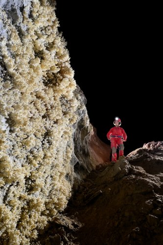 Grotte de Geophysicheskaya (Turkménistan) - Galerie des aiguilles : paroi couverte d'aragonite avec personnage en arrière plan.(SP-24-1452)