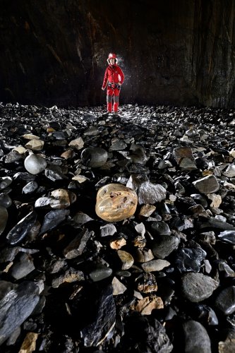 Gouffre de la Pierre Saint-Martin (Pyrénées-Atlantiques) - Plage de galets à la base de la salle de la Verna : galet rond en premier plan et spéléo an arrière plan(SP-24-2203)