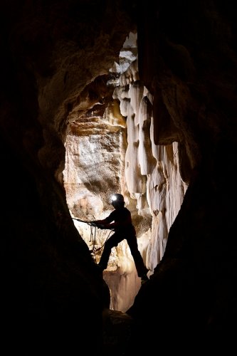 Aven de Keops (Alpes Maritimes) - Spéléo en silhouette en opposition au dessus d'un puits (chapelet de concrétions blanches an arrière plan)(SP-25-0510)
