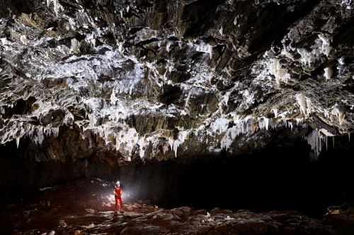 Gecko cave (Botswana) - Grande galerie sombre au sol rouge au plafond orné de concrétions blanches (SP-25-1017)