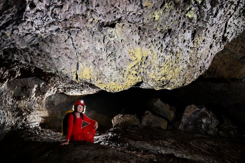 Cueva de Sucre (Isabela, Galapagos, Equateur) - Plafond du tube de lave  couvert de bactéries jaunes (personnage assis  en dessous)(SP-26-0185)