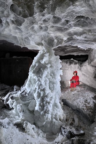Grotte de Geophysicheskaya (Turkménistan) - Salle Blanche : pilier massif de gypse hérissé de cristaux (avec personnage assis sur le côté)(SP-26-0419)