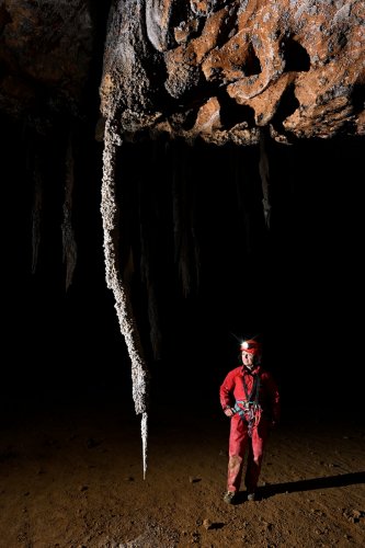 Cueva Canuela (Cantabrie, Espagne) - Grande stalactite en forme de sabre formée par le vent (personnage sur le côté)(SP-26-1055)