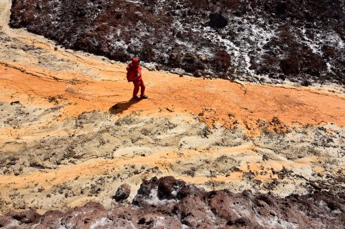 Iran (île d'Hormoz) - randonneuse dans vallée de Rangin Kaman progressant dans rivière sec jaune au milieu sel rouge(VO-16-0238)