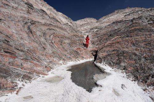 Iran (Montagnes du Zagros) - Dôme de sel de Dashti (Jashak salt dome) : personnage devant petite vasque d'eau avec dépôts de sel. Montagne de sel en arrière plan (VO-16-0420)
