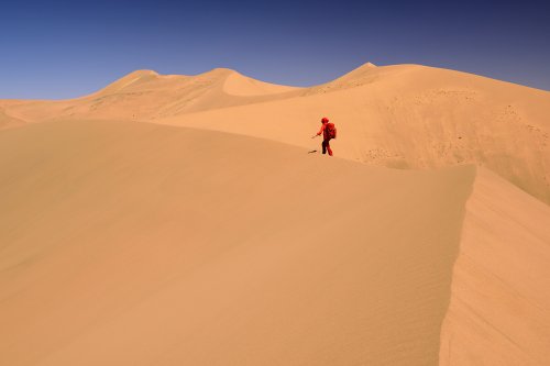 Désert du Badain Jaran (Chine, Mongolie Intérieure) - Enchaînement de dunes géantes avec randonneuse en rouge marchant sur la crête (VO-16-0865)