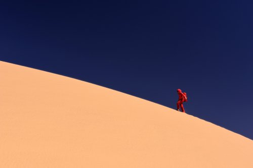 Désert du Badain Jaran (Chine, Mongolie Intérieure) - Randonneuse en rouge marchant sur la crête vue de profil.(VO-16-0882)