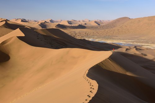 Désert du Badain Jaran (Chine, Mongolie Intérieure) - Vue générale d'un enchaînement de dunes avec randonneuse au loin sur la crête. Vallée avec lac salé à droite.(VO-16-0992)