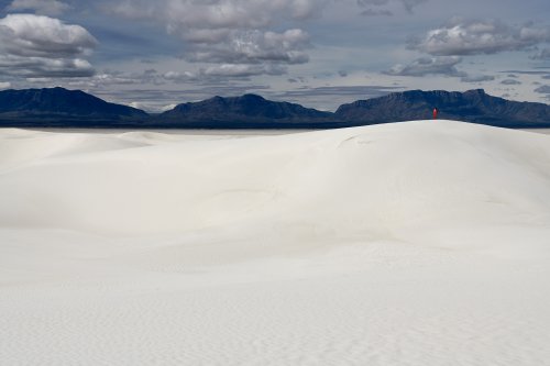 White Sands National Park (Nouveau Mexique, USA) - Dunes de sable blanc avec personnage en rouge sur la crête et montagnes sombres en fond(VO-20-0376)