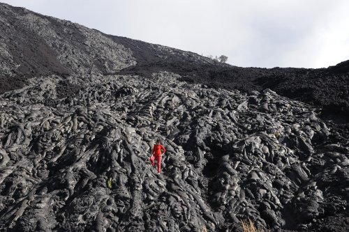 Hawaï - Volcano National Park (Big Island) - Chain of Craters Road  : Coulées de lave le long d'un talus. On distingue bien les laves pahoehoe sur lesquelles est le personnage, des laves aa, en arrière plan, plus noires et brisées.(vo-08-0173)