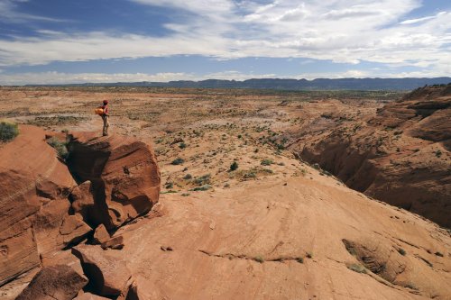 Parc d'Escalante (Utah). Secteur de Little Egypt. Vue surplombante du plateau avec personnage perché sur un rocher.(VOY 09-0946)
