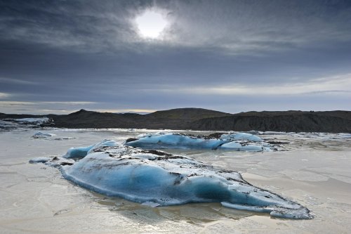 Islande (Skaftafell) : lagune au pied du glacier du Svinafellsjokull avec soleil pâle en contre jour(VO 11-0067)